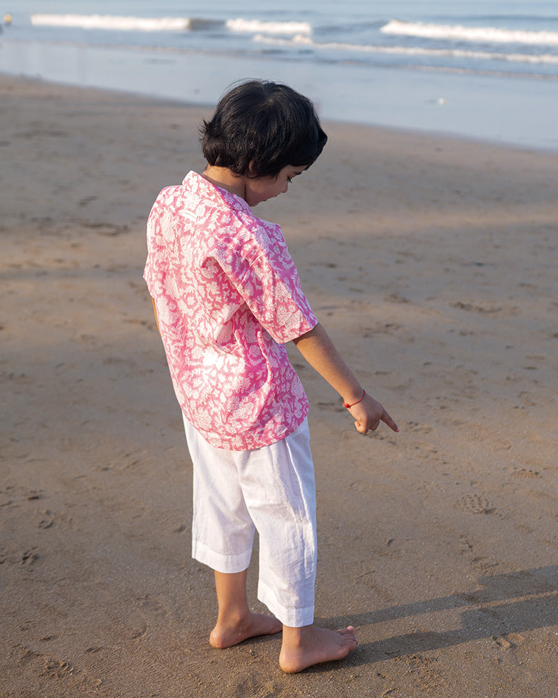 Light pink floral loose fit relaxed mul mul shirt for boys with a stylish cuban collar and natural coconut shell buttons made by handblock print artisans in Jaipur, Rajasthan.