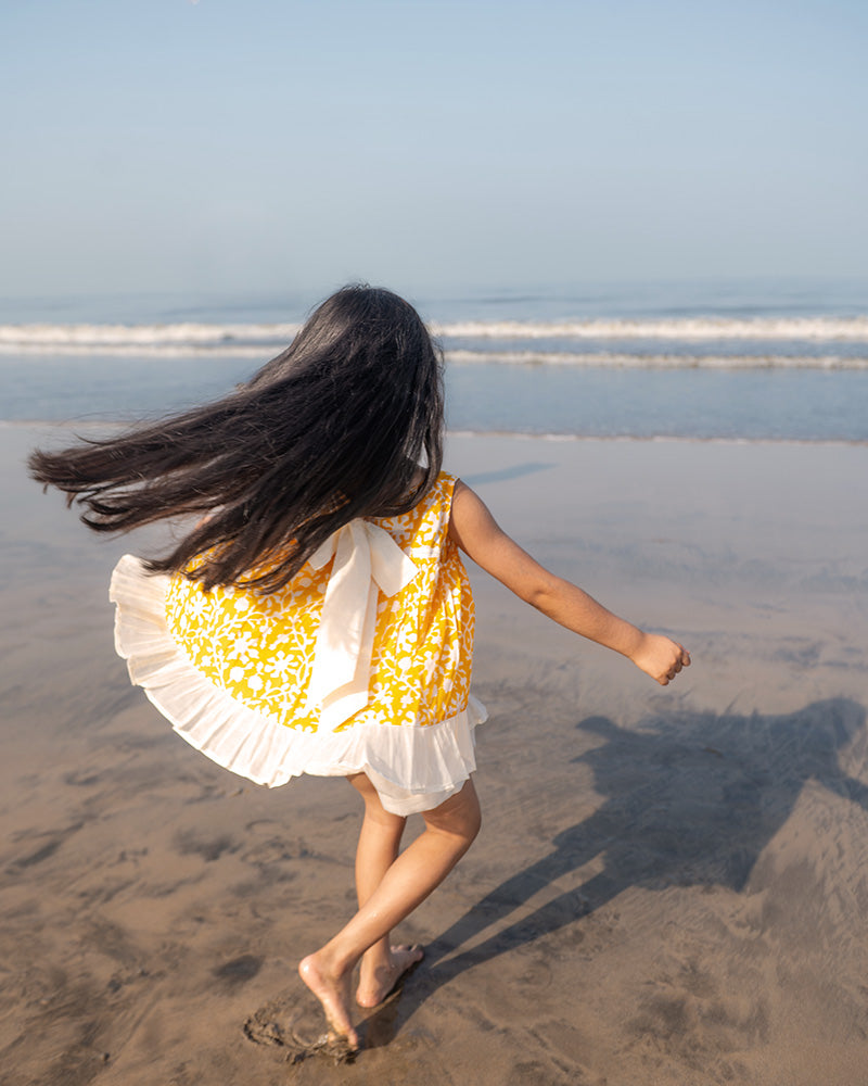 Coord set for girls with a yellow handblock printed voluminous flared style cotton top and kora handwoven shorts. Made with 100% soft and breathable cotton hand block printed in Jaipur, Rajasthan. The top is kedia styled flared with tie ups at the back for ease of wear. Shorts have a soft elasticated band on waist and come with pockets.