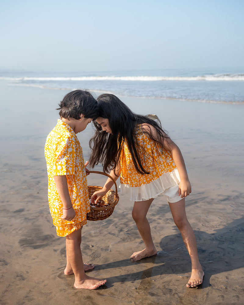 Coord set for girls with a yellow handblock printed voluminous flared style cotton top and kora handwoven shorts. Made with 100% soft and breathable cotton hand block printed in Jaipur, Rajasthan. The top is kedia styled flared with tie ups at the back for ease of wear. Shorts have a soft elasticated band on waist and come with pockets.