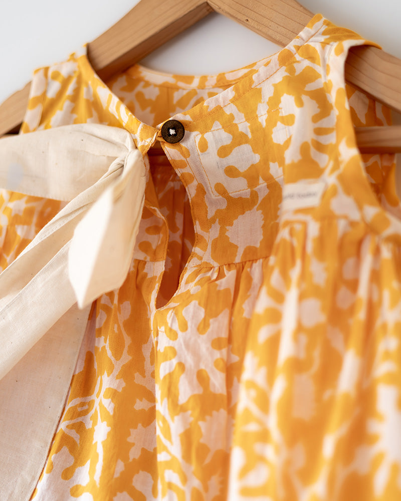 Coord set for girls with a yellow handblock printed voluminous flared style cotton top and kora handwoven shorts. Made with 100% soft and breathable cotton hand block printed in Jaipur, Rajasthan. The top is kedia styled flared with tie ups at the back for ease of wear. Shorts have a soft elasticated band on waist and come with pockets.