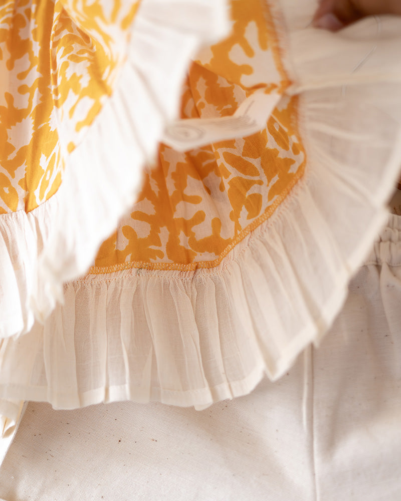 Coord set for girls with a yellow handblock printed voluminous flared style cotton top and kora handwoven shorts. Made with 100% soft and breathable cotton hand block printed in Jaipur, Rajasthan. The top is kedia styled flared with tie ups at the back for ease of wear. Shorts have a soft elasticated band on waist and come with pockets.