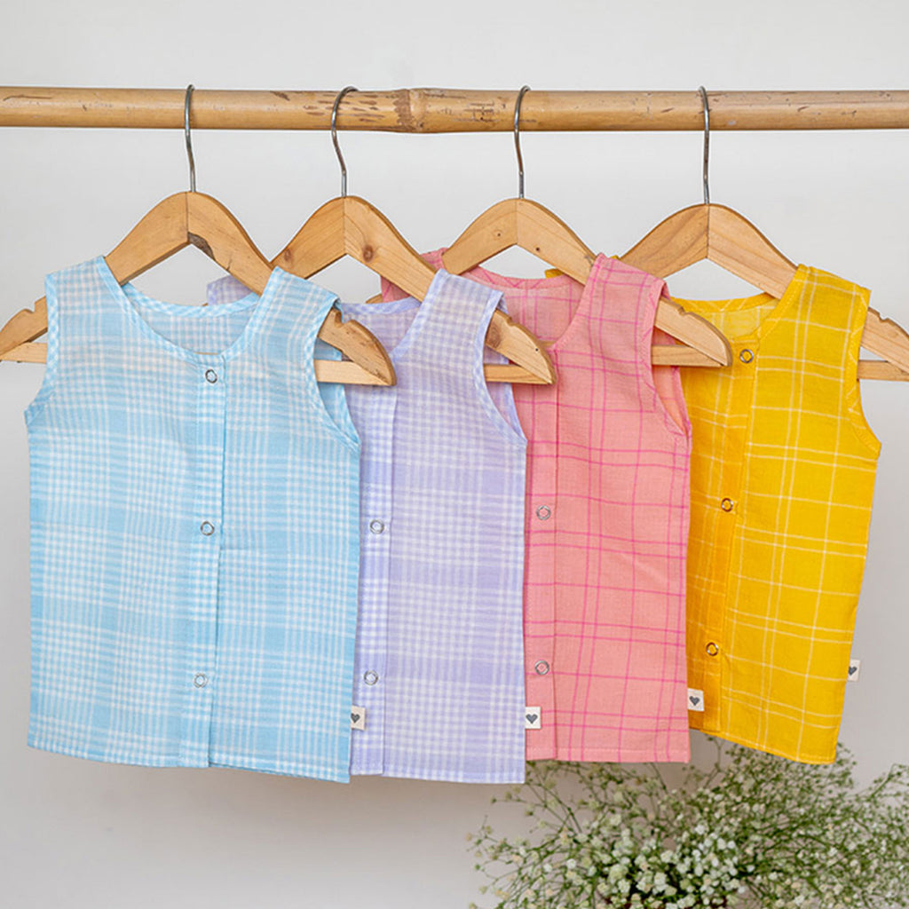 4 baby/infant/newborn jhablas in handwoven cotton checks hanging on a bamboo rod. They are in shades of blue, lavender, pink and yellow from left to right. 