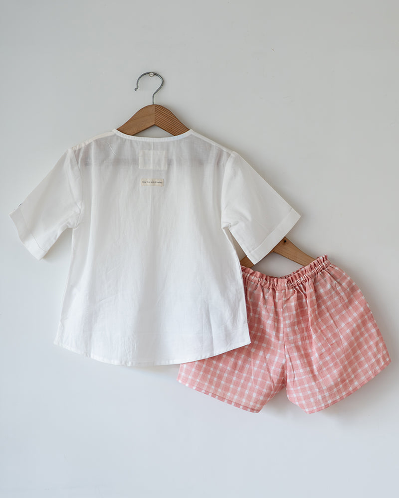 Unisex kids GOTS certified organic cotton white kurta and cotton peach shorts co ord set. 100% Cotton checkered Shorts hand block printed by artisans in Jaipur, Rajasthan. Kurta has pockets printed by hand block print. Shorts have soft elastication at waist for ease of wear.