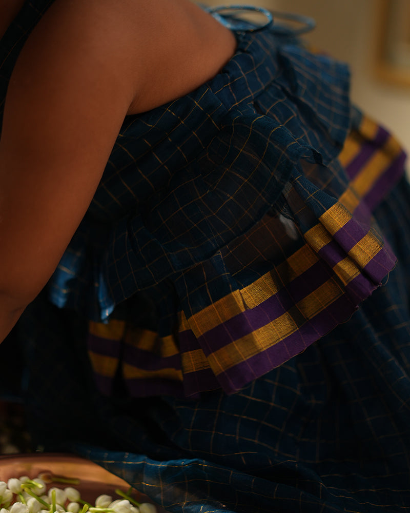 A girl wearing a deep teal blue colored cotton silk lehenga halter choli with golden checks handwoven by weavers in Maheshwar, Madhya Pradesh. Gathered skirt with ghera top Kids ethnic outfits, traditional clothing for kids. Silkwear for kids. Ghera skirt.