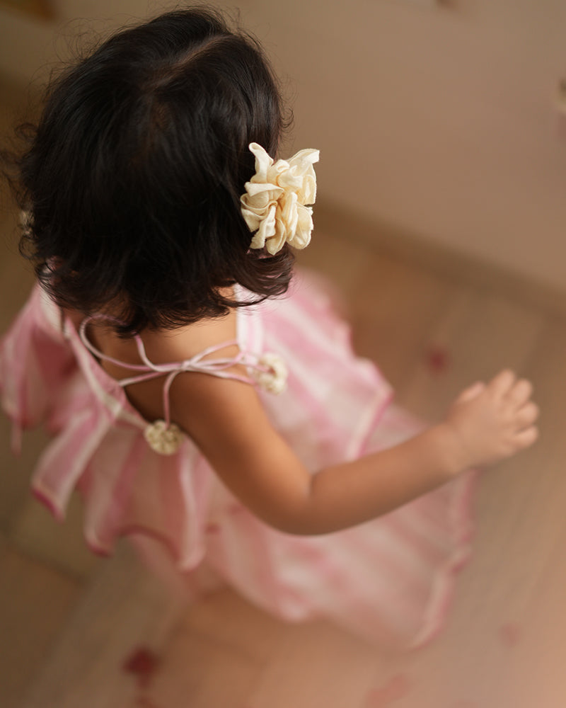 A girl wearing a cute baby pink and white striped cotton silk lehenga handwoven by weavers in Maheshwar, Madhya Pradesh. Kids ethnic outfits, traditional clothing for kids. Silkwear for kids. Kids hair accessories.