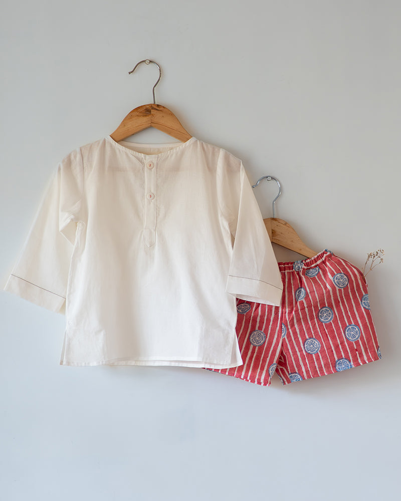 Unisex white cotton kurta and red shorts co ord set. 100% Cotton striped Shorts hand block printed by artisans in Jaipur, Rajasthan. Kurta made in GOTS certified organic cotton, has pockets and natural shell buttons.