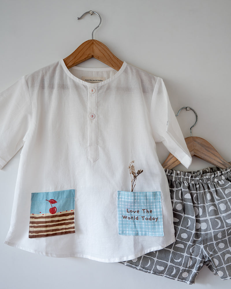 Unisex white cotton kurta and grey shorts co ord set. 100% Cotton checkered Shorts hand block printed by artisans in Jaipur, Rajasthan. Kurta made in GOTS certified organic cotton, has pockets printed by hand block print.
