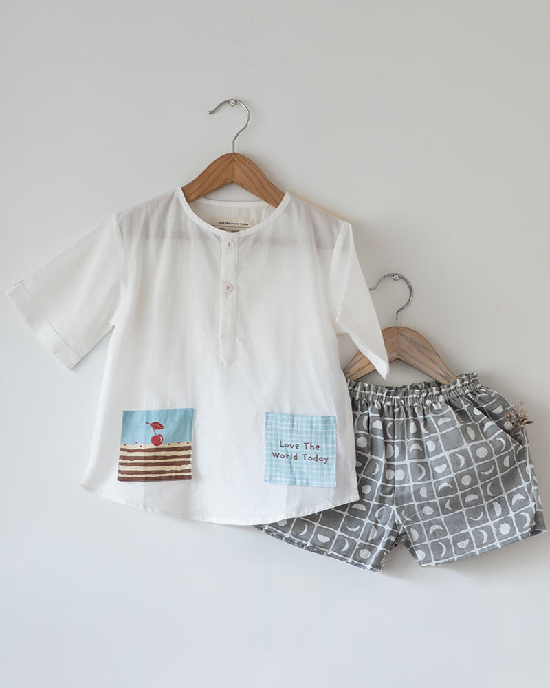 Unisex kids GOTS certified organic cotton white kurta and grey cotton shorts co ord set. 100% Cotton checkered Shorts hand block printed by artisans in Jaipur, Rajasthan. Kurta made in GOTS certified organic cotton, has pockets printed by hand block print.