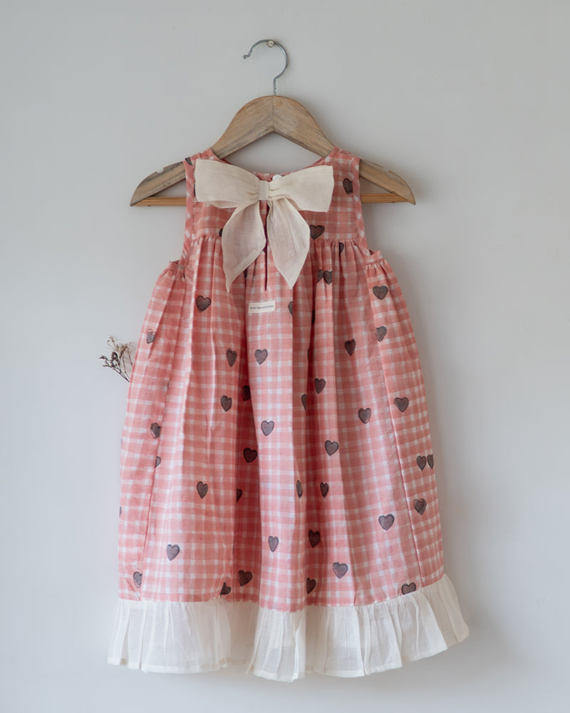 100% Cotton Night gown for girls hand block printed in a unique checks and heart print. Gown has back button and bow detail. Nightgown has pockets.