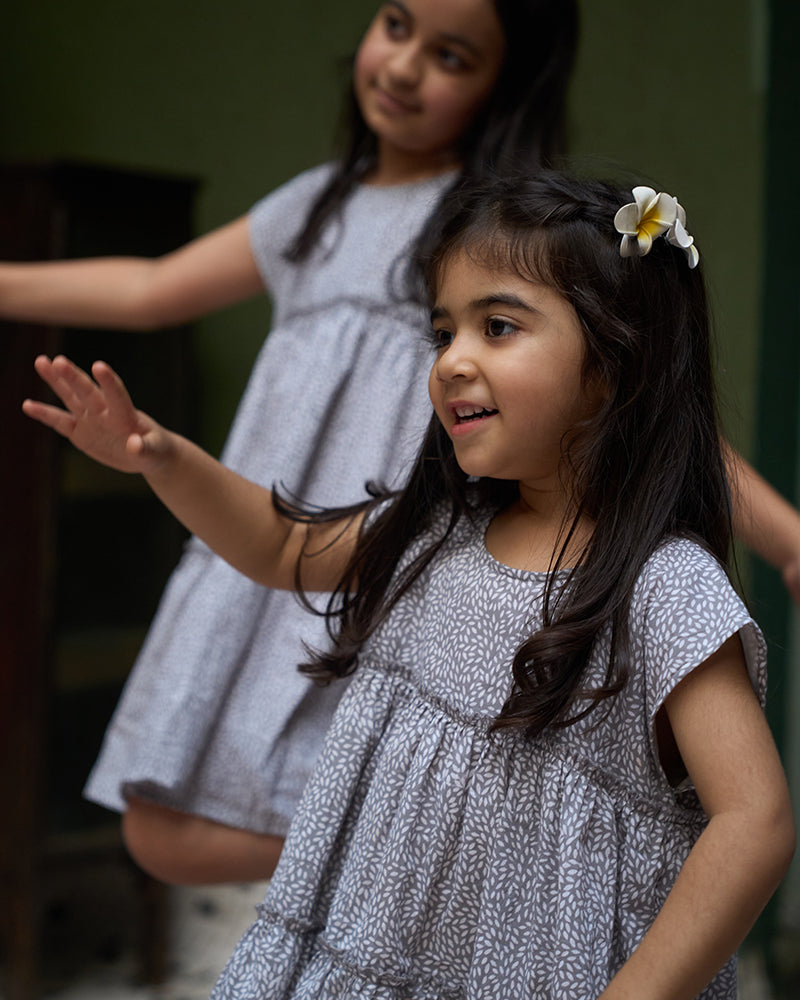 baby-girls-looking-at-themselves-in-the-mirror-dressed-in-matching-clothes-wearing-lovetheworldtodays-tiered-dress-in-grey-hand-block-print