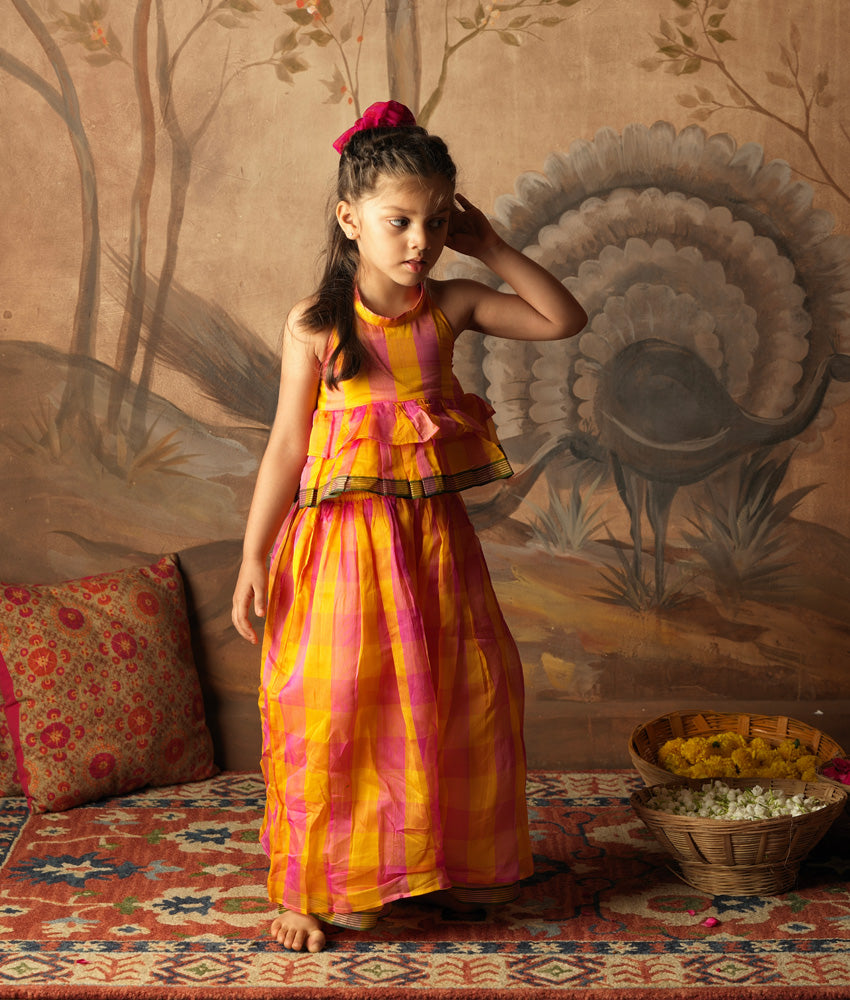 Pink and yellow checkered halter style tiered top with flared bottoms. Made in handwoven cotton silk. Perfect silk ethnic wear for girls.