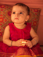 Red and pink checks sleeveless pleated dress for infants in handwoven cotton silk by artisans in Maheshwar Madhya Pradesh. Perfect for festivities like Navratri, diwali, Dussehra, dushehra, bhai dooj. Infant wear. Baby ethnic wear. Silkwear for babies. Baby girl festive wear. 
