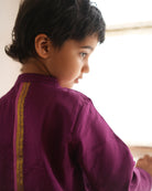 A Boy wearing a deep purple violet Indian festive Kurta with side buttons made with Handwoven cotton silk fabric woven by artisans in Maheshwar Madhya Pradesh.