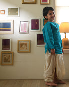 A Boy wearing a bright turquoise blue Indian festive Kurta with golden butti motifs made with Handwoven cotton silk fabric woven by artisans in Maheshwar Madhya Pradesh. This kids ethnic kurta is best for upcoming festivities like kids Navratri outfit, kids durga pooja kurta, Dussehra, dushehra, ethnic dress for Diwali, bhai dooj and kids/ boys kurta for weddings. Paired with an off white dhoti/ mundu. Perfect Kids silk wear, ethnic wear for kids, festive clothing for kids.