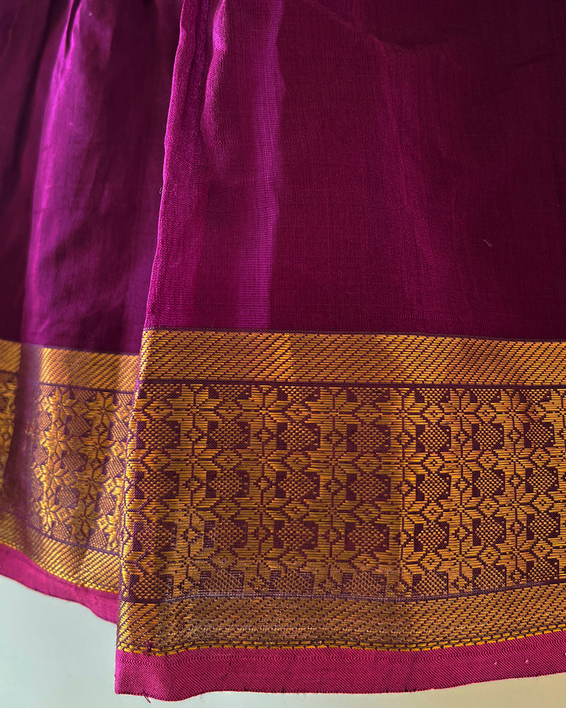 A deep purple violet sleeveless flared dress for infants in handwoven cotton silk by artisans in Maheshwar Madhya Pradesh. Perfect for festivities like Navratri, diwali, Dussehra, dushehra, bhai dooj. Infant wear. Baby ethnic wear. Silkwear for babies. Baby girl festive wear.  Broad border dress. 