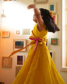 A girl wearing a bright yellow colored cotton silk lehenga handwoven by weavers in Maheshwar, Madhya Pradesh. This Maheshwari Cotton silk lehenga set is perfect for festivities like Navratri, durga pooja, Dussehra, dushehra, diwali pooja, bhai dooj and weddings. Kids ethnic outfits, traditional clothing for kids. Silkwear for kids.