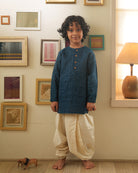 A Boy wearing a dark teal blue Indian festive Kurta with golden checks made with Handwoven cotton silk fabric woven by artisans in Maheshwar Madhya Pradesh. This kids ethnic kurta is best for upcoming festivities like kids Navratri outfit, kids durga pooja kurta, Dussehra, dushehra, ethnic dress for Diwali, bhai dooj and kids/ boys kurta for weddings. Paired with an off white dhoti/ mundu. Perfect Kids silk wear, ethnic wear for kids, festive clothing for kids.