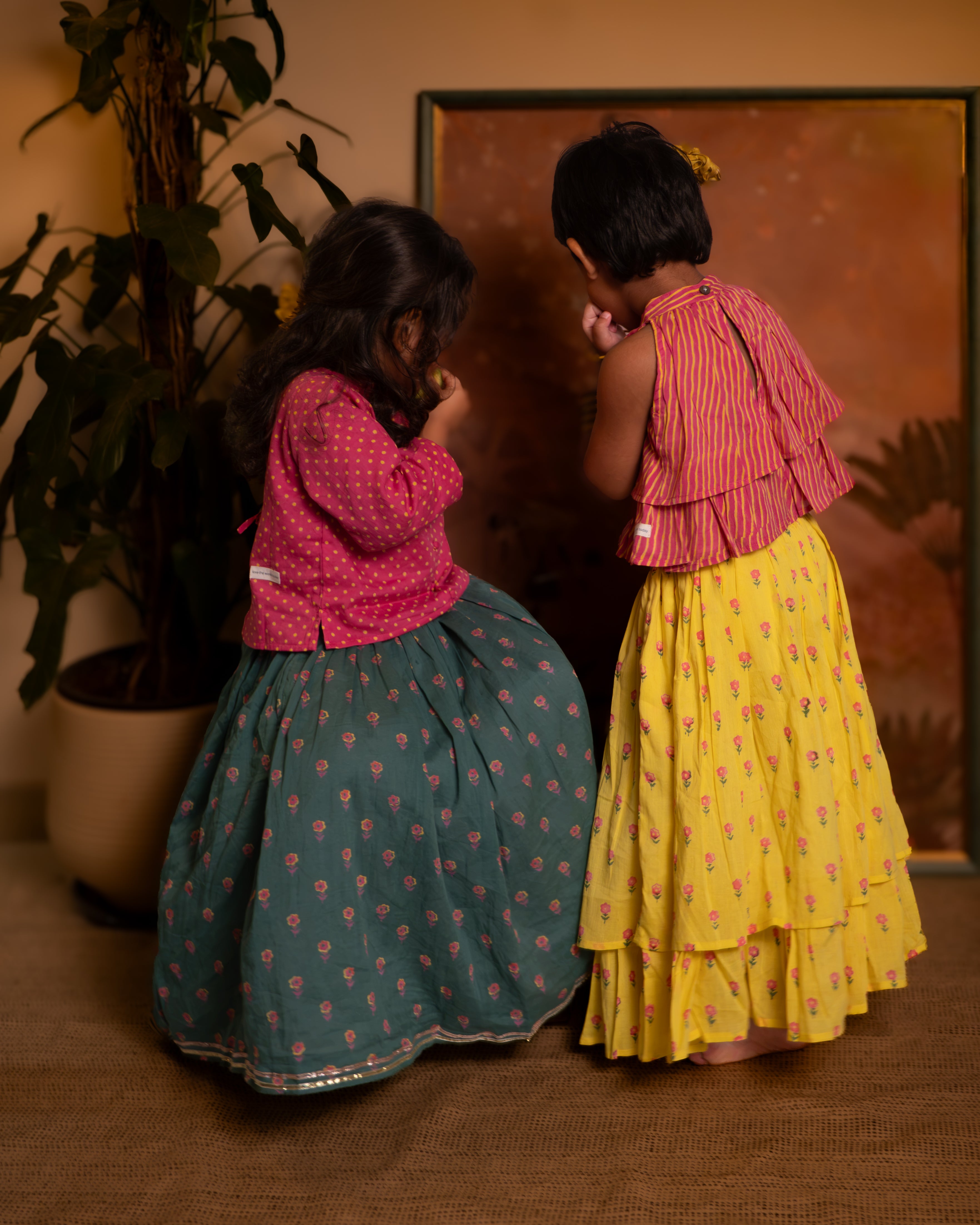 A Polka dot magenta pink hand block printed choli blouse with a dark green floral print lehenga set. Festive full sleeves blouse & gota lace skirt with pockets and tassels.