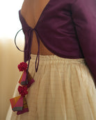 A girl wearing a deep purple wine colored cotton silk blouse with an off white a gold striped lehenga handwoven by weavers in Maheshwar, Madhya Pradesh. Tie back choli 
