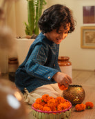 A Boy wearing a dark teal blue Indian festive Kurta with golden checks made with Handwoven cotton silk fabric woven by artisans in Maheshwar Madhya Pradesh. This kids ethnic kurta is best for upcoming festivities like kids Navratri outfit, kids durga pooja kurta, Dussehra, dushehra, ethnic dress for Diwali, bhai dooj and kids/ boys kurta for weddings. Paired with an off white dhoti/ mundu. Perfect Kids silk wear, ethnic wear for kids, festive clothing for kids. Kids celebrating diwali.