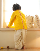 A Boy wearing a bright yellow Indian festive Kurta with side buttons made with Handwoven cotton silk fabric woven by artisans in Maheshwar Madhya Pradesh. This kids ethnic kurta is best for upcoming festivities like kids Navratri outfit, kids durga pooja kurta, Dussehra, dushehra, ethnic dress for Diwali, bhai dooj and kids/ boys kurta for weddings. Paired with an off white dhoti/ mundu. Perfect Kids silk wear, ethnic wear for kids, festive clothing for kids.