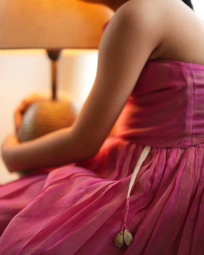 A girl wearing a cute pink and golden striped cotton silk coord set handwoven with silver polka dots by weavers in Maheshwar, Madhya Pradesh. Kaudi tie up. 