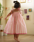A girl wearing a cute baby pink and white striped cotton silk lehenga handwoven by weavers in Maheshwar, Madhya Pradesh. This Maheshwari Cotton silk lehenga set is perfect for festivities like Navratri, durga pooja, Dussehra, dushehra, diwali pooja, bhai dooj and weddings. Kids ethnic outfits, traditional clothing for kids. Silkwear for kids. Skirt as dress. Dress skirt. 