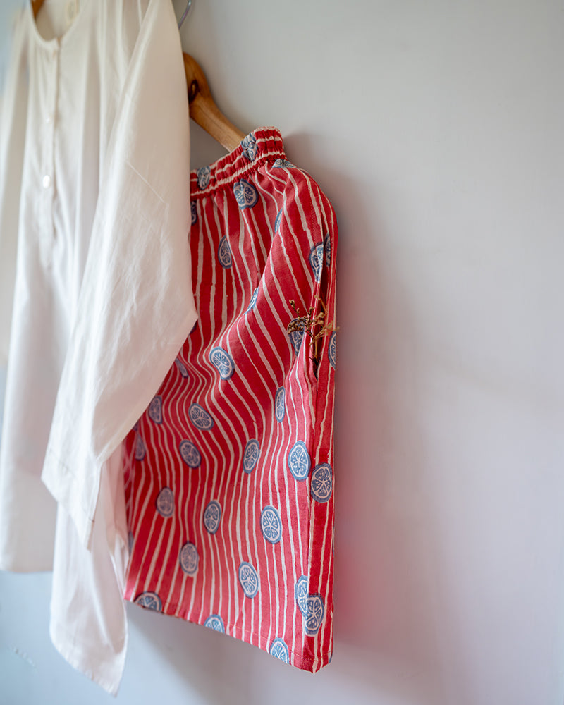 Unisex white cotton kurta and red shorts co ord set. 100% Cotton striped Shorts hand block printed by artisans in Jaipur, Rajasthan. Kurta made in GOTS certified organic cotton, has pockets and natural shell buttons.
