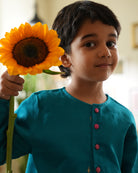 A Boy wearing a bright turquoise blue Indian festive Kurta with golden butti motifs made with Handwoven cotton silk fabric woven by artisans in Maheshwar Madhya Pradesh. This kids ethnic kurta is best for upcoming festivities like kids Navratri outfit, kids durga pooja kurta, Dussehra, dushehra, ethnic dress for Diwali, bhai dooj and kids/ boys kurta for weddings. Paired with an off white dhoti/ mundu. Perfect Kids silk wear, ethnic wear for kids, festive clothing for kids.