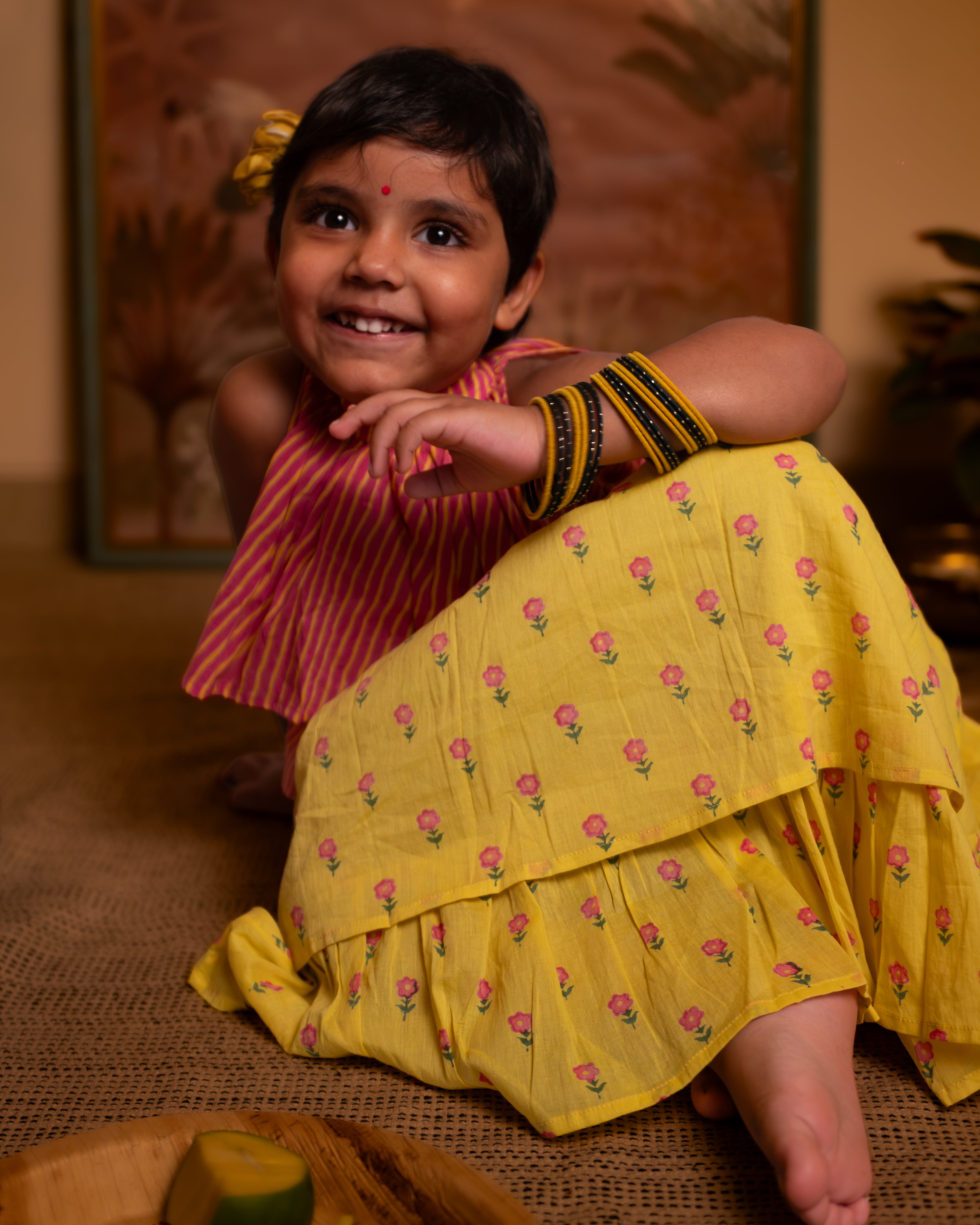 A chevron print lehariya hand block printed top with a bright yellow floral print lehenga. Festive sleeveless blouse & layered skirt with pockets set.