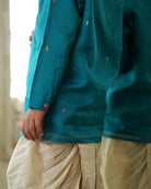 A Boy wearing a bright turquoise blue Indian festive Kurta with golden butti motifs made with Handwoven cotton silk fabric woven by artisans in Maheshwar Madhya Pradesh. Paired with an off white dhoti/ mundu. Perfect Kids silk wear, ethnic wear for kids, festive clothing for kids.