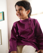A Boy wearing a deep purple violet Indian festive Kurta with side buttons made with Handwoven cotton silk fabric woven by artisans in Maheshwar Madhya Pradesh. Perfect Kids silk wear, ethnic wear for kids, festive clothing for kids.