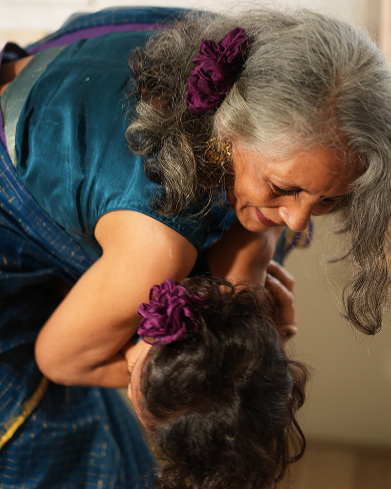 A woman wearing a deep teal blue colored cotton silk saree with golden checks handwoven by weavers in Maheshwar, Madhya Pradesh. Dadi poti love. Grandmother , grand mom, nani with daughter. 