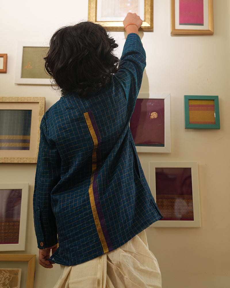 A Boy wearing a dark teal blue Indian festive Kurta with golden checks made with Handwoven cotton silk fabric woven by artisans in Maheshwar Madhya Pradesh. 