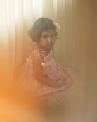 A girl wearing a cute baby pink and white striped cotton silk lehenga handwoven by weavers in Maheshwar, Madhya Pradesh.