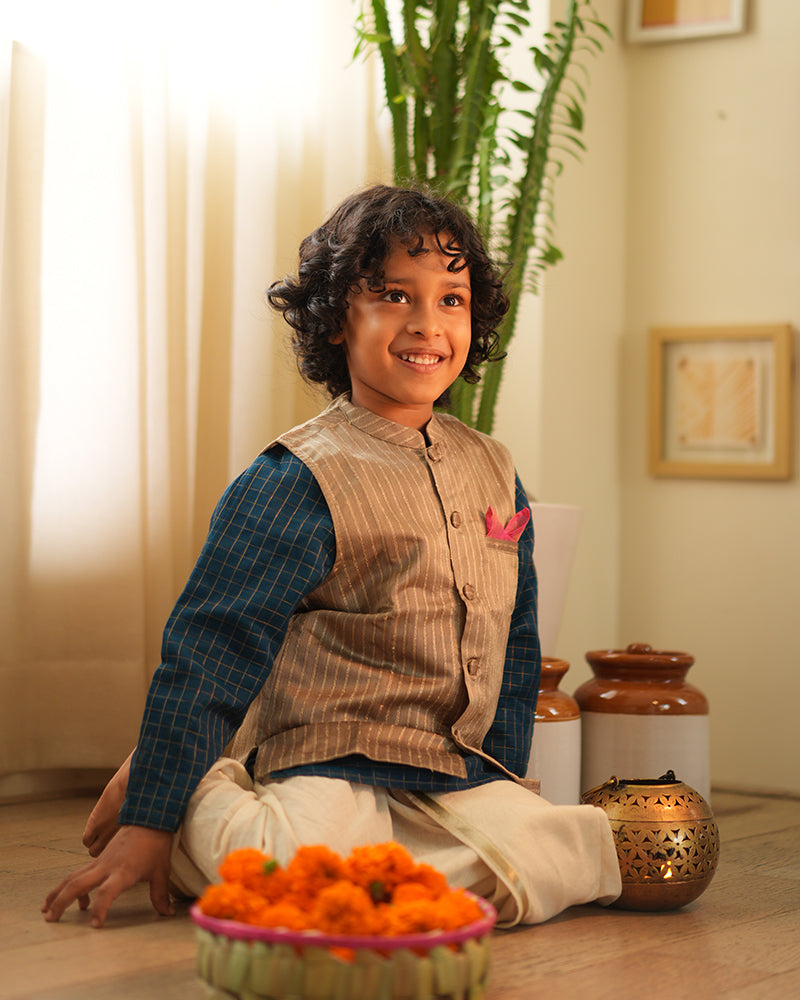 A Boy wearing a steel grey Indian festive bandi nehru jacket with golden stripes made with Handwoven cotton silk fabric woven by artisans in Maheshwar Madhya Pradesh. This kids ethnic kurta is best for upcoming festivities like kids Navratri outfit, kids durga pooja kurta, Dussehra, dushehra, ethnic dress for Diwali, bhai dooj and kids/ boys kurta for weddings. Paired with an off white dhoti/ mundu. Perfect Kids silk wear, ethnic wear for kids, festive clothing for kids.