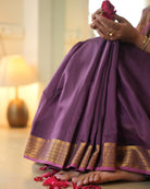 A woman wearing a deep purple wine colored cotton silk saree handwoven by weavers in Maheshwar, Madhya Pradesh. This Maheshwari Cotton silk saree is perfect for festivities like Navratri, durga pooja, Dussehra, dushehra, diwali pooja, bhai dooj and weddings. Paired with a golden blouse. Women's silk wear, silk saree for women, cotton silk saree, heavy pallu border sarees. 
