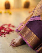 A woman wearing a deep purple wine colored cotton silk saree handwoven by weavers in Maheshwar, Madhya Pradesh. Women's silk wear, silk saree for women, cotton silk saree, heavy pallu border sarees. 