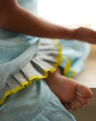 A girl wearing a cute light baby blue and yellow cotton silk sharara suit set handwoven with silver polka dots by weavers in Maheshwar, Madhya Pradesh. 