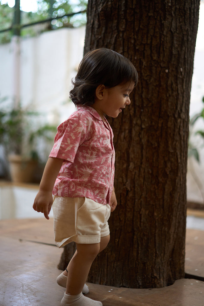 sweet-little-boy-wearing-kids-half-sleeve-casual-holiday-shirt-with-pink-floral-handblock-print-in-soft-and-breathable-cotton-with-white-handwoven-shorts
