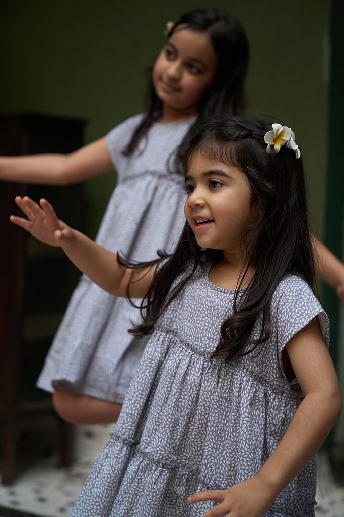 baby-girls-looking-at-themselves-in-the-mirror-dressed-in-matching-clothes-wearing-lovetheworldtodays-tiered-dress-in-grey-hand-block-print