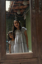 baby-girls-looking-at-themselves-in-the-mirror-dressed-in-matching-clothes-wearing-lovetheworldtodays-tiered-dress-in-grey-hand-block-print