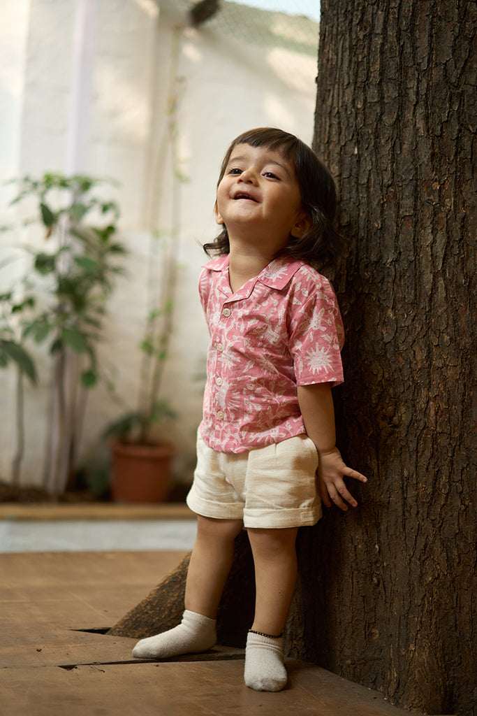 sweet-little-boy-wearing-kids-half-sleeve-casual-holiday-shirt-with-pink-floral-handblock-print-in-soft-and-breathable-cotton-with-white-handwoven-shorts