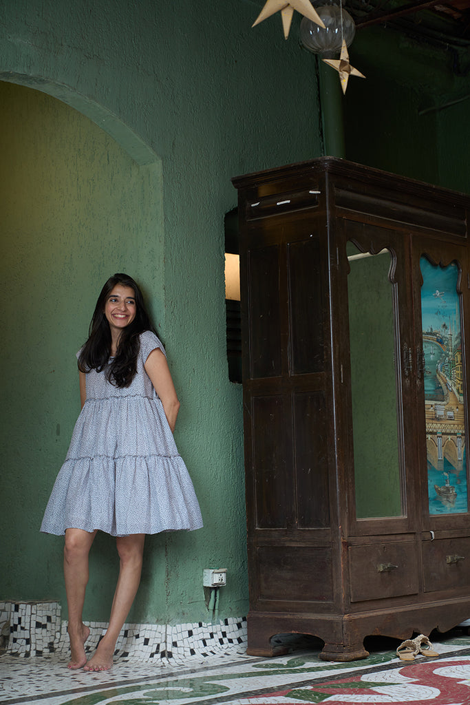 woman-dressed-in-twirl-dress-with-cap-sleeves-tiered-dress-in-grey-hand-block-print